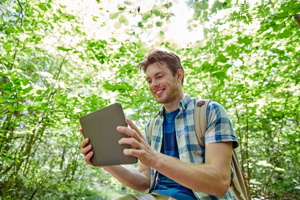 Glücklicher Mann mit Rucksack und Tablet-PC im Wald — Stockfoto