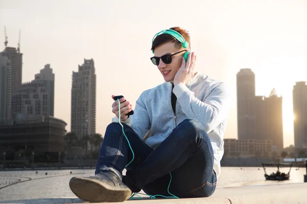 Glücklicher junger Mann mit Kopfhörer und Smartphone — Stockfoto