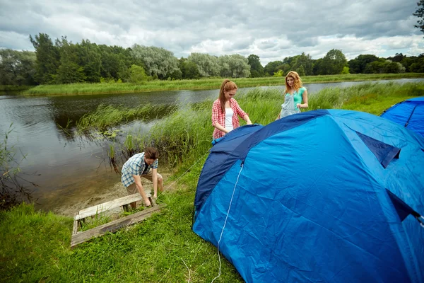 Grupo de amigos sonrientes instalando carpa al aire libre —  Fotos de Stock