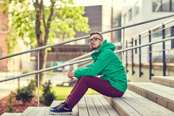 Feliz joven hipster hombre sentado en las escaleras en la ciudad —  Fotos de Stock