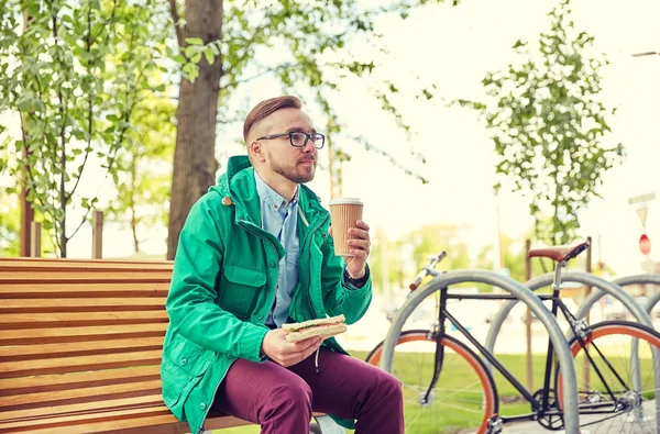 Feliz jovem hipster homem com café e sanduíche — Fotografia de Stock