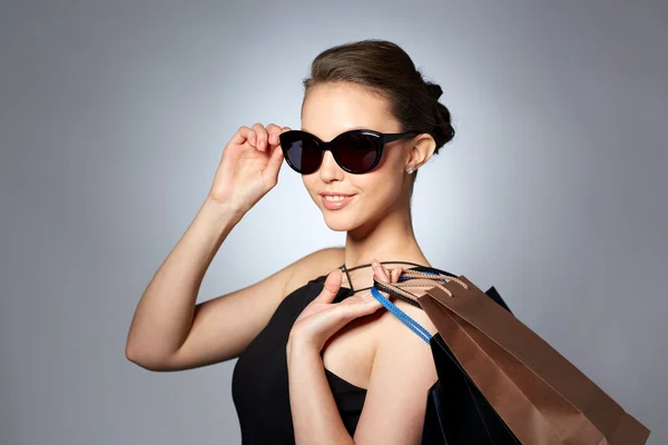 Mulher feliz em óculos de sol pretos com sacos de compras — Fotografia de Stock