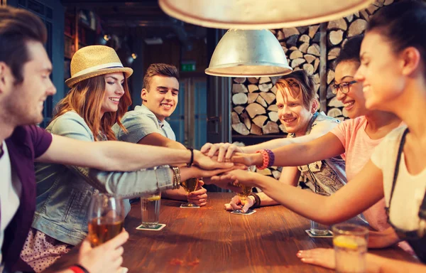 Happy přátelé s nápoji a rukama nahoře v baru — Stock fotografie