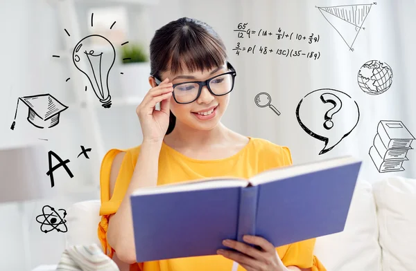 Smiling young asian woman reading book at home — Stock Photo, Image