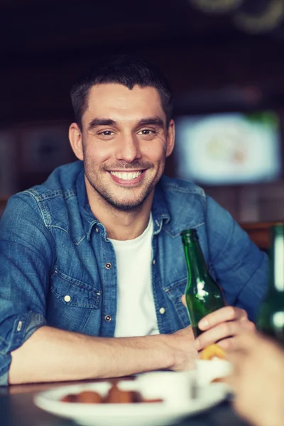 Jovem feliz bebendo cerveja no bar ou pub — Fotografia de Stock