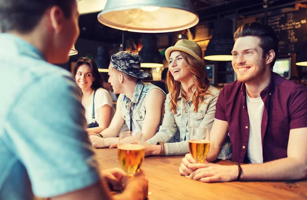 Счастливые друзья пьют пиво и разговаривают в баре — стоковое фото