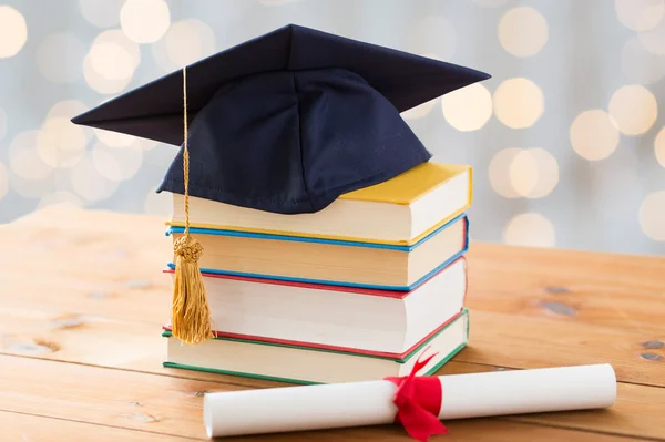 Close up of books with diploma and mortarboard — Stock Photo, Image