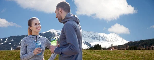 Pareja sonriente con botellas de agua al aire libre — Foto de Stock