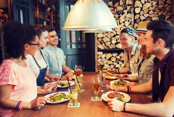 Happy friends eating and drinking at bar or pub — Stock Photo, Image