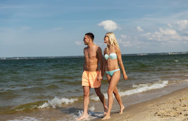 Счастливая пара в купальниках гуляющая по летнему пляжу — стоковое фото