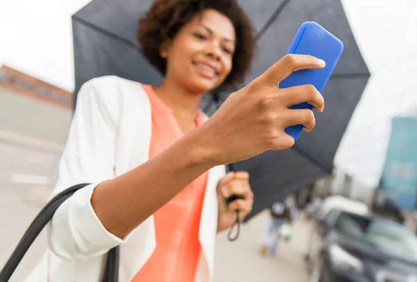 Närbild på kvinna med paraply och smartphone — Stockfoto