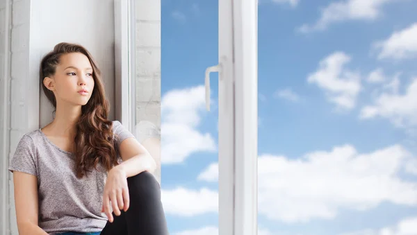 Triste chica adolescente bonita sentada en el alféizar de la ventana —  Fotos de Stock