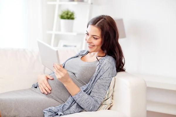 Glad gravid kvinna med tablett dator hemma — Stockfoto