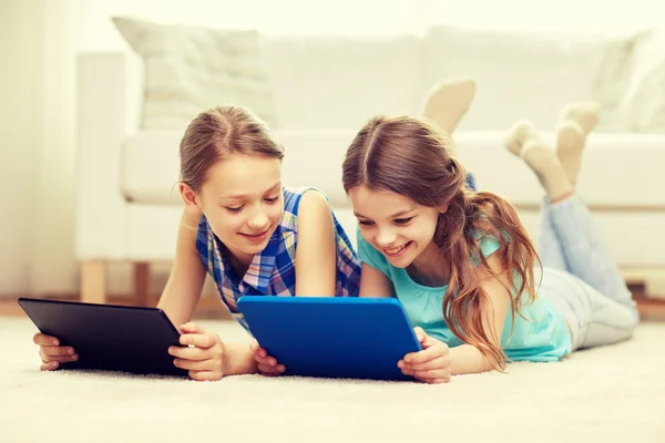 Chicas felices con la tableta de la PC acostado en el suelo en casa —  Fotos de Stock