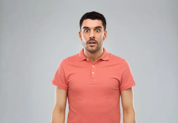 Hombre sorprendido en polo camiseta sobre fondo gris —  Fotos de Stock