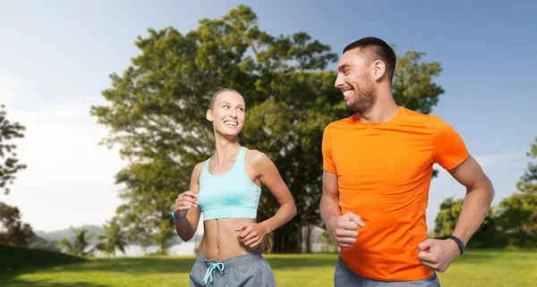 Sonriente pareja corriendo sobre verano parque fondo — Foto de Stock