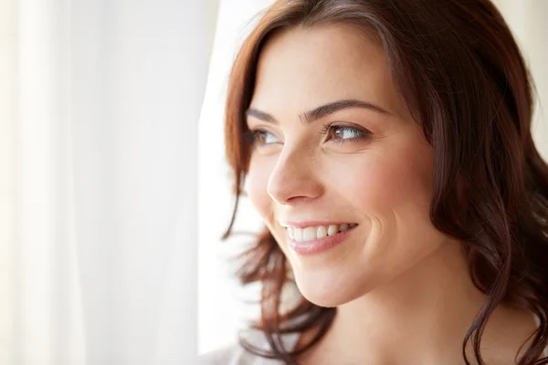 Gelukkig jonge vrouw op zoek via venster thuis — Stockfoto