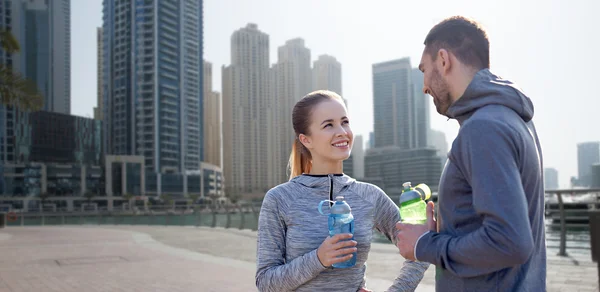 Pareja sonriente con botellas de agua en la ciudad —  Fotos de Stock