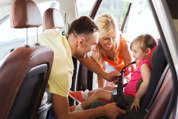 Feliz padres abrochando niño con cinturón de seguridad de coche — Foto de Stock