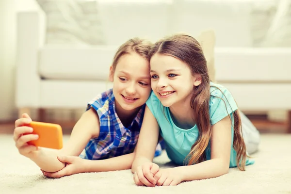 Meninas felizes com smartphone levando selfie em casa — Fotografia de Stock