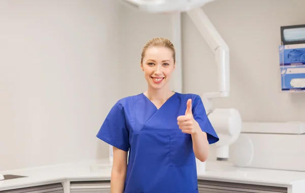 Happy female dentist showing thumbs up at clinic — Φωτογραφία Αρχείου