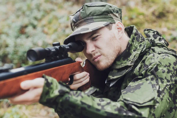 Jovem soldado ou caçador com arma na floresta — Fotografia de Stock