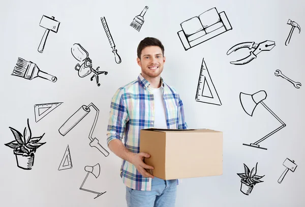 Smiling young man with cardboard box at home — Stock Photo, Image