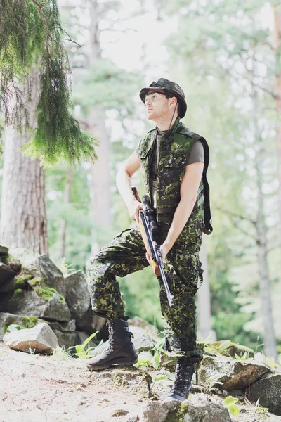 Young soldier or hunter with gun in forest — Stock Photo, Image