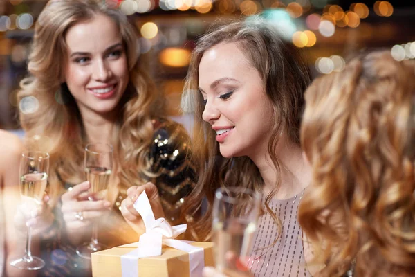 Mulheres felizes com champanhe e presente no clube noturno — Fotografia de Stock