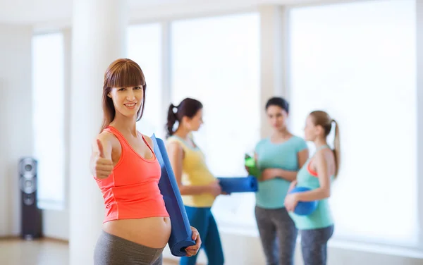 Gravid kvinna med matta visar tummen i gymmet — Stockfoto