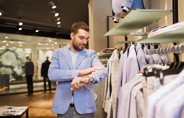 Happy young man trying jacket on in clothing store — Stock Photo, Image