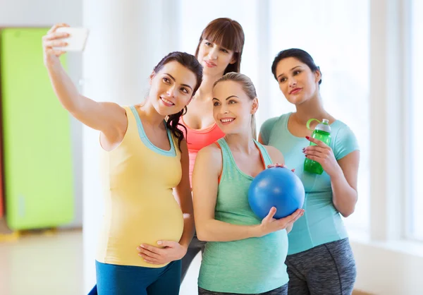 Mujeres embarazadas tomando selfie por teléfono inteligente en el gimnasio —  Fotos de Stock