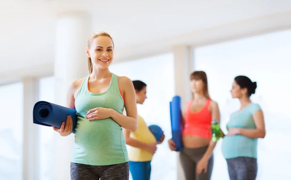 Mujer embarazada feliz con estera en el gimnasio — Foto de Stock