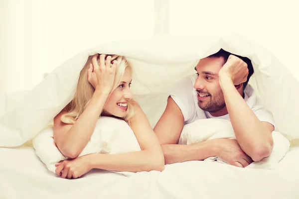 幸せなカップルのベッドで横になっていると家で話しています。 — ストック写真