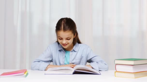 Chica de la escuela feliz lectura libro o libro de texto en casa — Vídeos de Stock