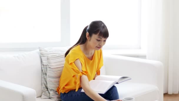 Smiling young asian woman reading book at home — Stock Video