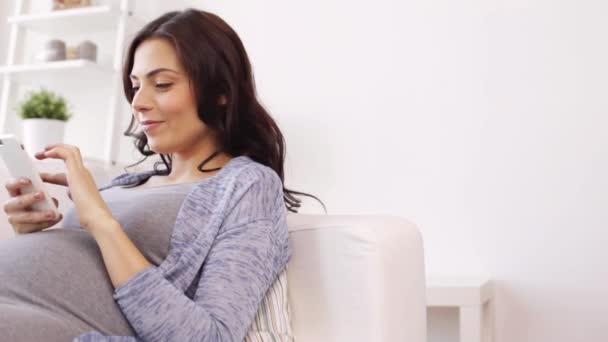 Gelukkig zwanger vrouw met smartphone thuis — Stockvideo
