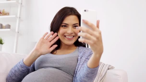 Беременная женщина в видео чате на смартфоне дома — стоковое видео
