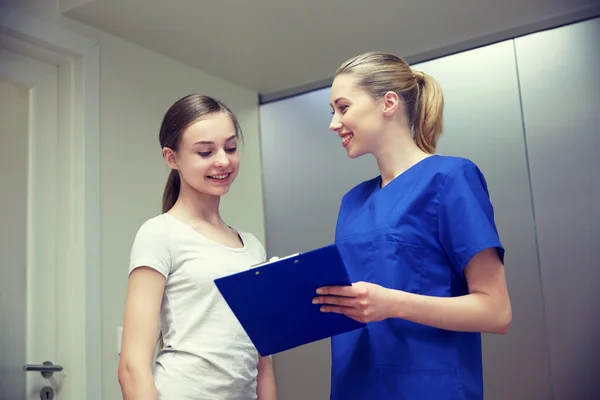 Χαμογελαστά νοσοκόμα με πρόχειρο και κορίτσι στο νοσοκομείο — Φωτογραφία Αρχείου