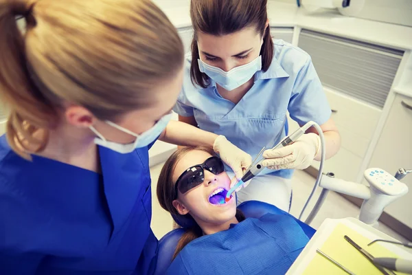 Dentistas mujeres que tratan los dientes de niña paciente —  Fotos de Stock