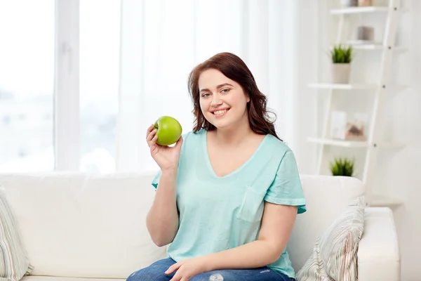 Feliz plus size mulher comer maçã verde em casa — Fotografia de Stock