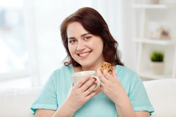 Feliz mulher plus size com copo e biscoito em casa — Fotografia de Stock