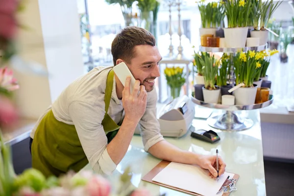 Homem com smartphone fazendo notas na loja de flores — Fotografia de Stock