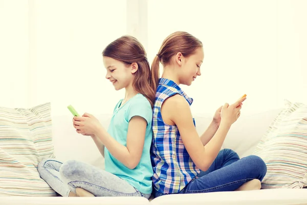 Chicas felices con teléfonos inteligentes sentados en el sofá — Foto de Stock