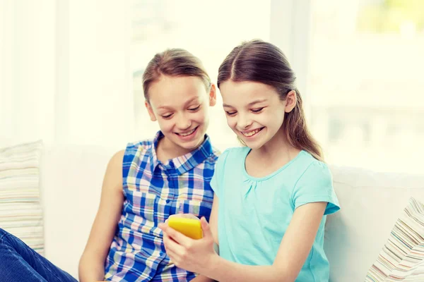 Happy girls with smartphone sitting on sofa — Stock Photo, Image