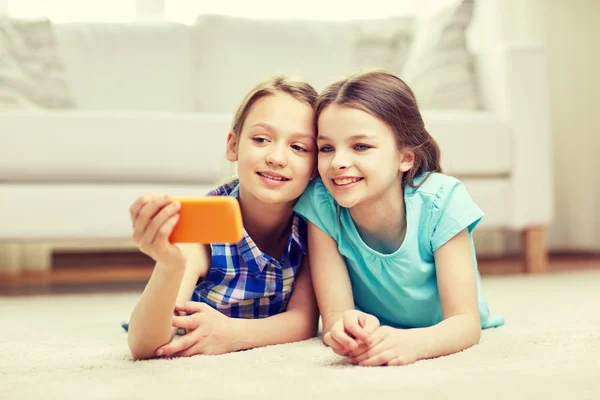 Meninas felizes com smartphone levando selfie em casa — Fotografia de Stock