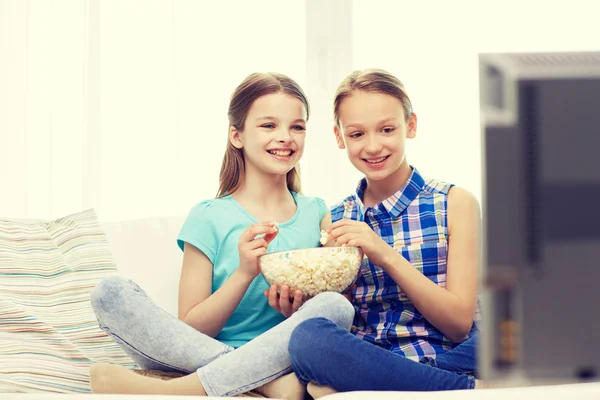 Glada tjejer med popcorn tittar på tv hemma — Stockfoto