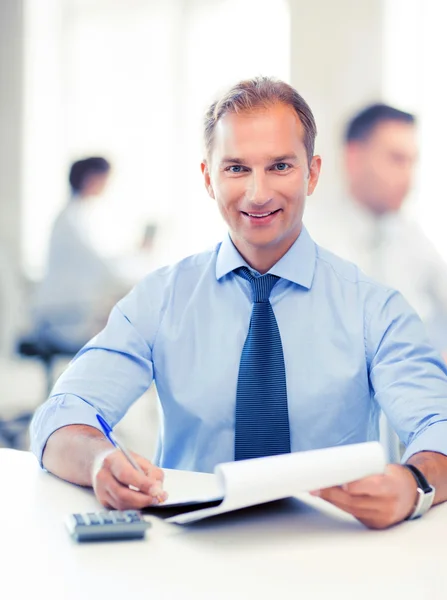 Geschäftsmann mit Notizbuch und Taschenrechner im Büro — Stockfoto