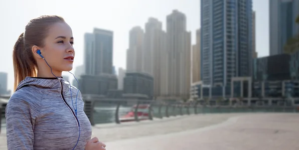 Šťastná žena s sluchátka, běh přes město Dubaj — Stock fotografie