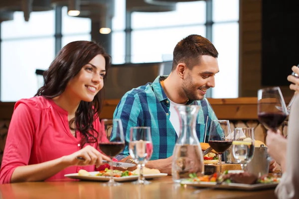 Lyckliga par med vänner äta på restaurang — Stockfoto